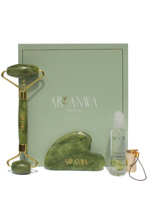 Rouleur facial en jade vert, outil gua sha et sérum éclat cristal avec applicateur devant une boîte verte Ar Anwa Skincare.