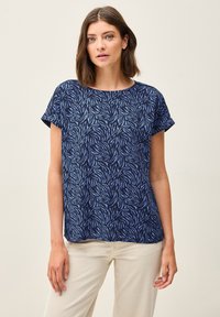 Haut à manches courtes bleu marine ornée d'un motif de feuilles dans des tons de bleu clair. Tissu doux avec un col rond et une coupe décontractée.