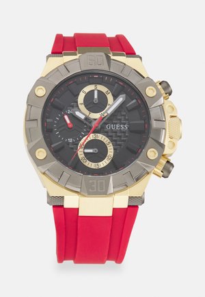Orologio cronografo nero con accenti dorati e cinturino in gomma rossa. Presenta tre sottodial, quadrante texturizzato e grandi numeri arabi.