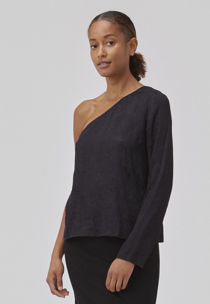 Black, textured, one-shoulder top with long sleeve and a relaxed fit, made from a lightweight fabric. Smooth surface, minimal detailing.