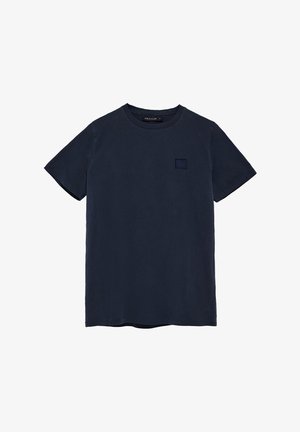 Camiseta de manga corta azul marino hecha de algodón. Presenta un pequeño parche de logo cuadrado tonal en el área del pecho izquierdo. Diseño liso con cuello redondo.