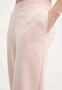 Lichtroze sweatpants van zachte stof, voorzien van kleine rhinestones en het 'GUESS' logo in zilver gedrukt op het voorzakgebied.