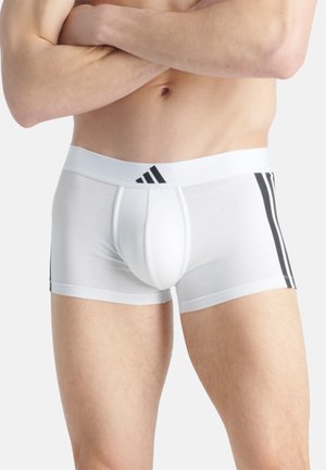 Boxers ajustados para hombres blancos de color blanco, que presentan rayas negras a los lados y una cinturilla elástica blanca con un logo negro.