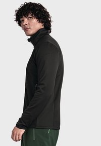 Schwarze Fleecejacke mit hohem Kragen, Reißverschluss vorne und strukturiertem Stoff. Verfügt über ein dezentes Logo auf der linken Schulter und ein elegantes Design.