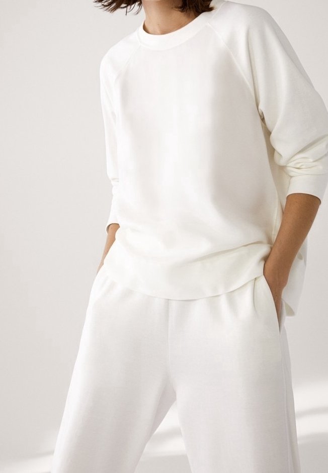 Witte katoenen sweatshirt met raglanmouwen, in combinatie met bijpassende losse witte broek, met een zachte textuur en een elastische tailleband.