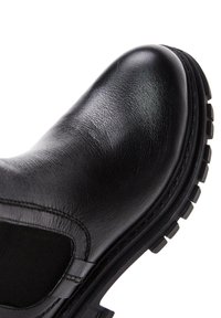 Stivale in pelle nera con punta arrotondata, pannelli laterali elastici e suola in gomma texturizzata con profondi intagli per aderenza e stabilità.
