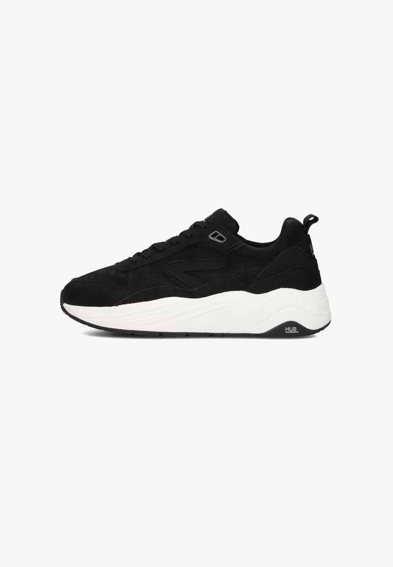 Zwarte suède sneaker met een witte tussenzool, voorzien van een ronde neus, platte veters, een gewatteerde kraag en een geprofileerde zool met merkdetails.