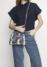 Kolorowa, teksturowana torba na ramię z wzorem skóry węża. Posiada podwójne uchwyty oraz regulowany pasek. Na neutralnym tle.