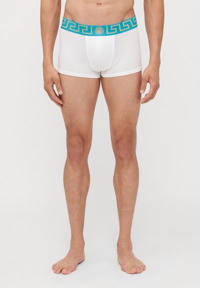 Weiße Baumwoll-Boxershorts mit einem blauen dekorativen Bund, der ein griechisches Schlüsselmustern und ein zentrales Logo aufweist. Mittellange Beine, bis zur Mitte des Oberschenkels.