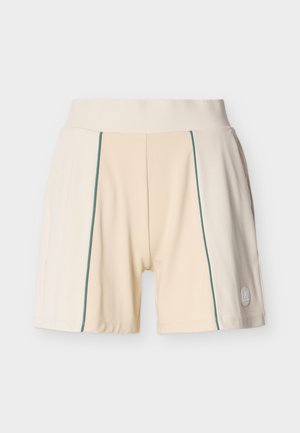 Bēšas sporta šortus ar platu vidukļa joslu, zaļām vertikālām šuvēm priekšpusē un mazu apaļu logotipu uz labās apakšējās kājas.