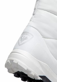 Weißer Sportschuh mit gepolstertem Obermaterial, strukturierten Paneelen und auffälligem Logo. Verfügt über eine Gummisohle mit Traktionsmustern für besseren Halt.