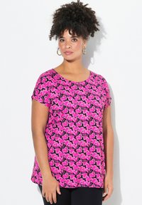 Top de manga corta hecho de tela rosa con un patrón de mariposas negras. Presenta un escote redondo y un diseño de corte relajado.