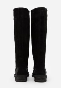Bottes noires en daim montantes avec une texture douce, un design droit, des coutures renforcées et un talon bloc solide.