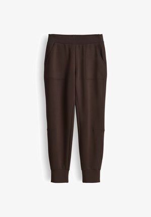 Bruine joggingbroek met een elastische tailleband, zijzakken, aansluitende boorden en naaddetails langs de benen. Gemaakt van zachte stof.