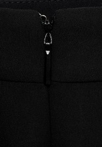 Černá látka s uzavřením na zip nahoře. Zip má elegantní design s kovovým táhlem, umístěným na texturovaném pozadí.