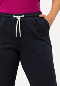 Marine joggingsbroek van zachte stof, met een elastische tailleband met witte trekkoord en zijzakken voor praktisch gebruik.