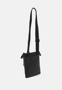 Borsa a tracolla in pelle nera con finitura testurizzata, forma rettangolare, tracolla regolabile e zip sulla parte superiore. Design minimalista.