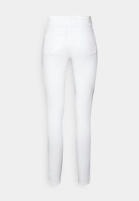 Jeans blancos ajustados con cintura alta, cuatro bolsillos y una textura suave y elástica. Sin patrones visibles ni detalles de hardware.