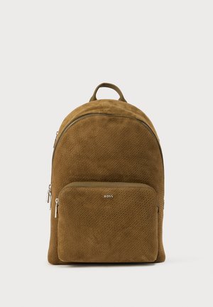 Zaino in suede marrone con superficie testurizzata, forma arrotondata, tasca frontale con zip e maniglia superiore. Presenta dettagli in argento come la cerniera e il logo.