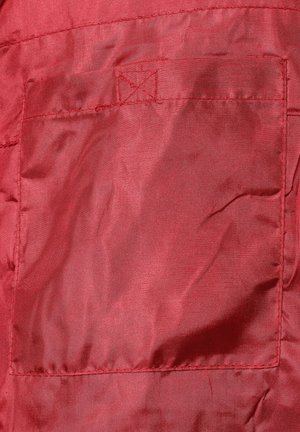 Tela de satén roja con un bolsillo rectangular con detalle de costura cuadrada. Textura suave y ligero brillo son prominentes.