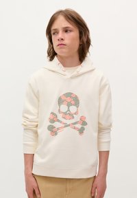 Crème-kleurige hoodie met een doodskop en gekruiste botten ontwerp, versierd met bloempatronen in groen en roze. De capuchon heeft lichte perzikkleurige accenten.