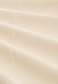 Tela de color crema con una textura suave, que presenta pliegues sutiles y un patrón de tejido consistente y uniforme. Ideal para diversas aplicaciones textiles.