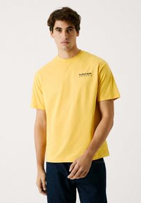 Gul bomulds t-shirt med korte ærmer. Har et lille sort "Red Bull Racing" logo på venstre bryst. Lige nederkant og klassisk pasform.