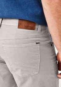 Light gray pants feature a leather label at the waistband and a back pocket with contrasting stitching. The fabric has a smooth texture.