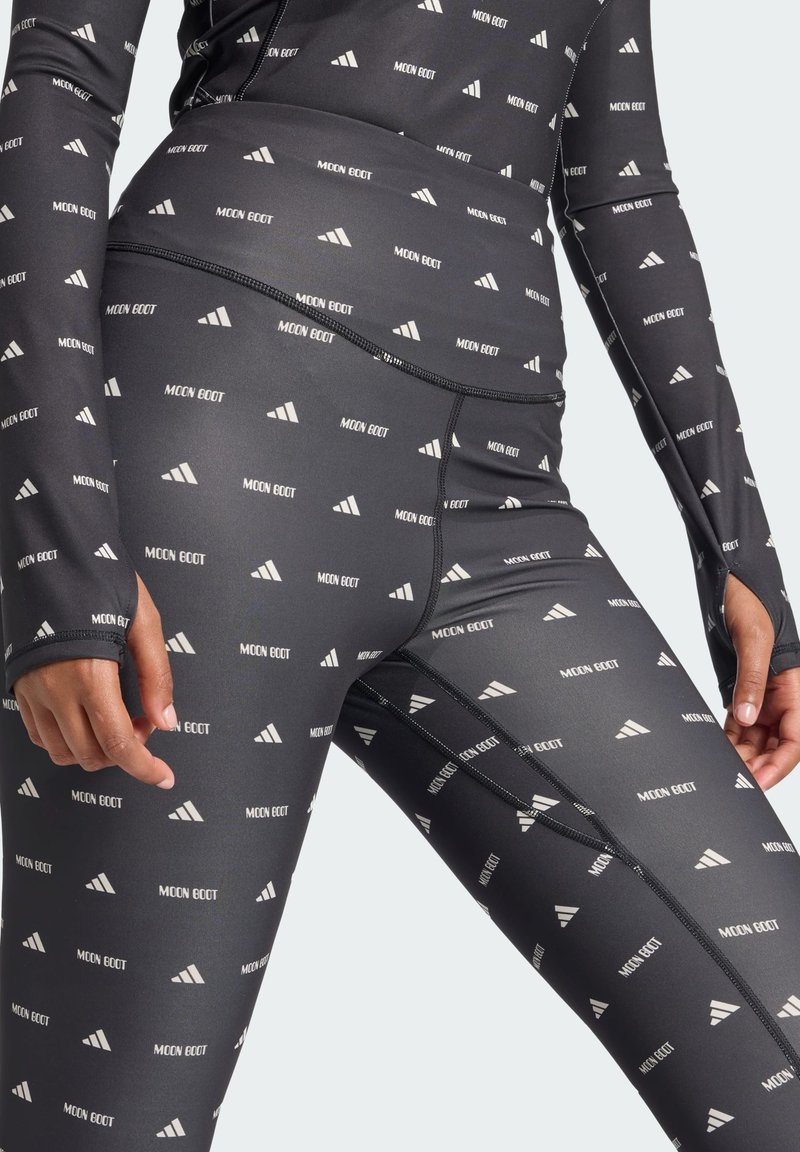 Leggings atléticos negros con un patrón de logotipos blancos repetido. Presentan una tela lisa y elástica, costuras reforzadas y orificios para los pulgares en los puños.