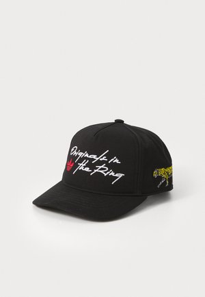 Boné preto de algodão com texto bordado "Original in The Ring" em branco, logótipo vermelho da Adidas e um gráfico de leopardo amarelo de lado.