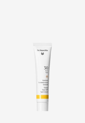 Tube de crème solaire teintée pour le visage Dr. Hauschka, SPF 30, blanche avec une bande jaune et texte en allemand et anglais.