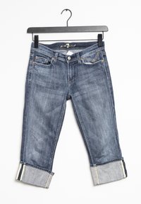 Jeans de mezclilla en azul oscuro, con un corte recto y puños dobles, cinturilla en contraste y bolsillos frontales en ángulo con detalles de costura.