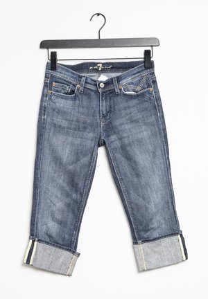 Jeans de mezclilla en azul oscuro, con un corte recto y puños dobles, cinturilla en contraste y bolsillos frontales en ángulo con detalles de costura.