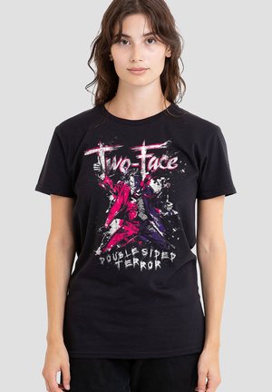 Woman wearing black t-shirt with graphic of Two-Face character in red and purple suit holding guns, text reads "Two-Face Doublesided Terror."