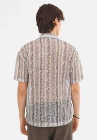 Kurzarmhemd aus transparentem, gemustertem Stoff in Erdtönen, mit Kragen und geradem Saum, das vertikale Streifen und florale Designs zeigt.