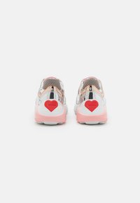 Tenisky s lesklým stříbrným a růžovým designem, mají síťovaný svršek, bílou podrážku a červený srdíčkový detail na patě. Značka viditelná po stranách.