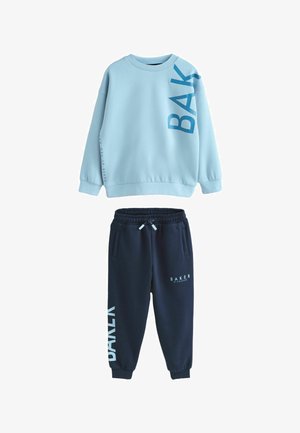 Felpa azzurro chiaro con scritte blu scuro evidenti e pantaloni della tuta blu navy con logo bianco, vita con coulisse e tasche laterali.