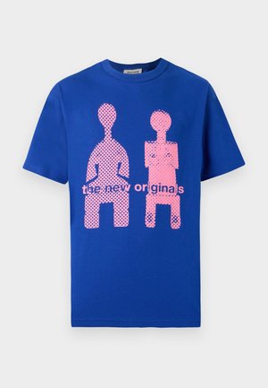 Camiseta de algodón azul con un diseño gráfico de dos figuras abstractas en rosa con lunares y el texto "los nuevos originales" abajo.