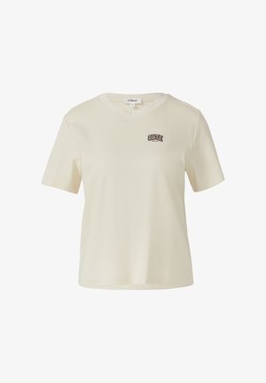 Kreem lühikeste varrukatega puuvillane T-särk ümmarguse kaelusega ja väikese musta ja pruuni tekstiga "CUTE SINCE BIRTH" vasakul rinnal.