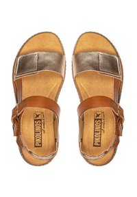 Sandalias de cuero marrón con acentos metálicos dorados, hebilla ajustable, plantillas acolchadas y una base texturizada. Marca "Pikolinos" visible.