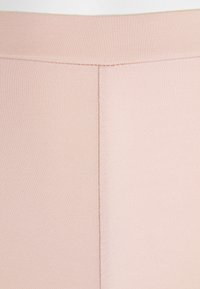 Lichtroze legging gemaakt van gladde, rekbare stof met een brede, elastische tailleband. Kenmerkt zich door een effen kleur en nette stikdetails.
