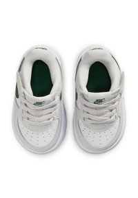 Ein Paar weiße Nike-Sneaker für Kleinkinder mit grünem Innenfutter und Logo, von oben auf einem weißen Hintergrund betrachtet.