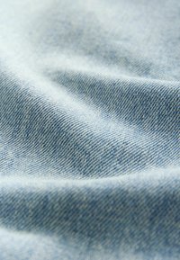 Ljust blå denimtyg med en slät textur, som har en lätt glans och diagonalt vävmönster. Mjuk och flexibel i utseendet.
