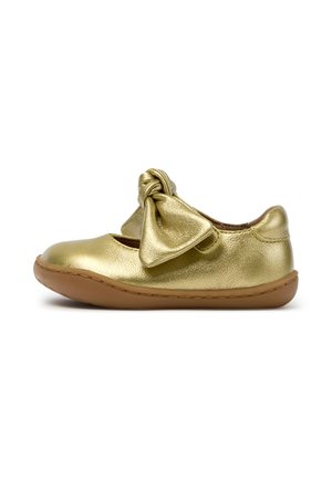 Chaussure plate de couleur dorée avec un grand nœud sur le dessus et une semelle marron flexible, taille enfant, vue latérale sur fond blanc.