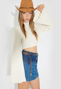 Virkat krämfärgad cropped topp med utsvängda ärmar, kombinerad med en denim mini kjol med knäppning fram och brunt bälte med charmdetaljer.