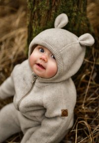 Beiger Fleece-Strampler mit einem Reißverschluss vorne, gerippten Bündchen und Bärenohren an der Kapuze. Verfügt über ein kleines braunes Logo-Patch an der Seite.