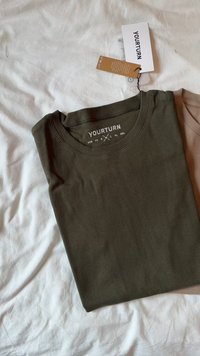 Khaki rebrast maica s kratkimi rokavi z okroglo izrezom. Na etiketi je navedena blagovna znamka "YOURTURN." Tkanina se zdi mehka in gladka, lepo zložena na beli površini.