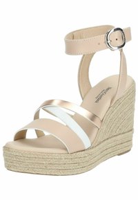 Sandalo con zeppa e suola in juta intrecciata, cinturini sintetici beige e bianchi, e un accento metallico. Presenta una cinghia alla caviglia con chiusura a fibbia.