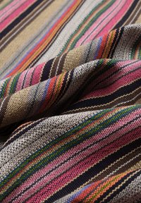 Geborduurd textiel met horizontale strepen in roze, groen, bruin en zwart. De stof heeft een gestructureerde uitstraling met variërende dikte.