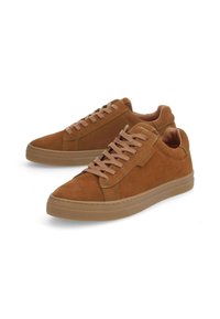 Baskets en daim marron avec un design bas, dotées de lacets beiges, d'une semelle en caoutchouc texturée et de minimalistes accents de couture sur les côtés.